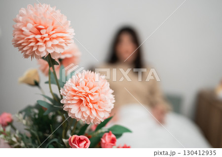 Serene Indoor Scene with Flowers and a Relaxed Figure in the Background 130412935