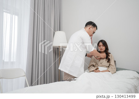A Doctor examines a patient carefully in a modern medical examination room A Doctor examines a patient carefully in a modern medical examination room 130413499