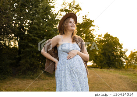 Pregnant woman in summer dress enjoying nature outdoors Pregnant woman in summer dress enjoying nature outdoors 130414014