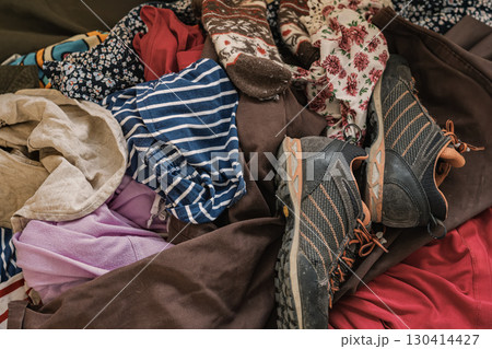 Mixed pile of worn clothes and used shoes symbolizing textile waste and recycling challenges. Concept of zero waste, sustainable living, circular fashion Mixed pile of worn clothes and used shoes symbolizing textile waste and recycling challenges. Concept of zero waste, sustainable living, circular fashion 130414427