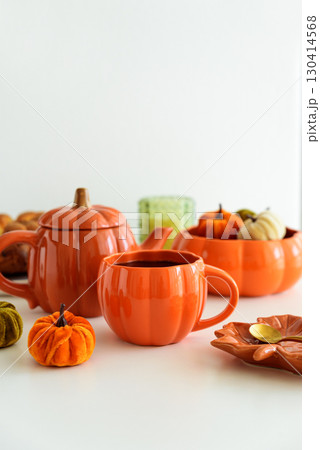 Autumnal tea set with pumpkin decor and cake on a white table. 130414568