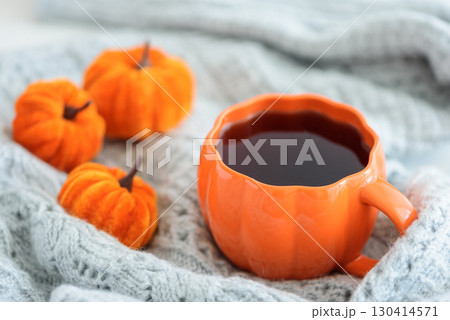 Autumnal tea set with pumpkin decor on a cozy knitted blanket. 130414571