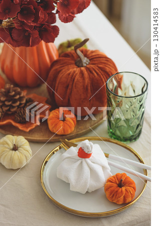 Thanksgiving table setting with decorative pumpkins, candles and string lights on white wooden table 130414583