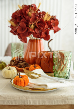 Thanksgiving table setting with decorative pumpkins, candles and string lights on white wooden table 130414584