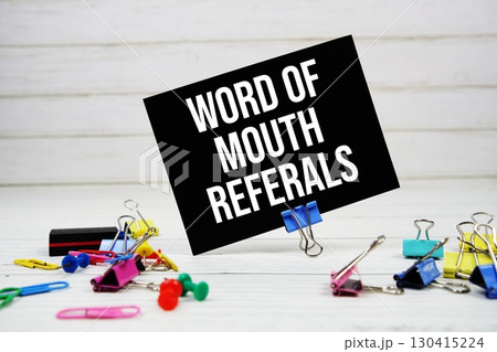 Word Of Mouth Referrals text on paper card with stationary on wooden background Word Of Mouth Referrals text on paper card with stationary on wooden background 130415224