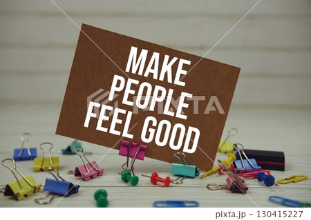 Make People Feel Good text on paper card with stationary on wooden background Make People Feel Good text on paper card with stationary on wooden background 130415227