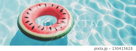 Bright summer sunlight illuminating an inflatable watermelon ring floating on a turquoise swimming pool, creating a vibrant scene perfect for relaxation and summer fun 130415628