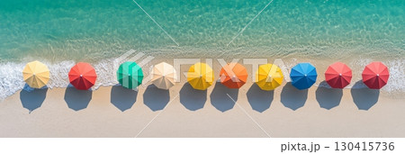 Aerial view of a pristine beach with a row of colorful parasols casting long shadows on the white sand, waves gently lapping at the shore, creating a vibrant and inviting summer holiday scene Aerial view of a pristine beach with a row of colorful parasols casting long shadows on the white sand, waves gently lapping at the shore, creating a vibrant and inviting summer holiday scene 130415736