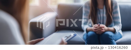 Psychologist taking notes while listening to her patient explaining her problems during a psychotherapy session on a comfortable sofa in the office 130416260