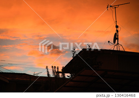 鮮やかなオレンジ色に染まる夕焼け空と住宅のシルエット 130416468