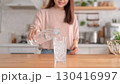 グラスに水を注ぐ女性 130416997