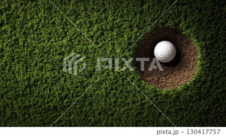 White golf ball falling into the hole on a perfectly manicured green grass, representing a successful putt and the achievement of a golfing goal 130417757