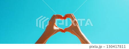 Woman making heart shape with hands against blue sky in a sunny day, expressing love, care, togetherness and bonding, perfect image for valentine's day, mother's day or woman's day 130417811