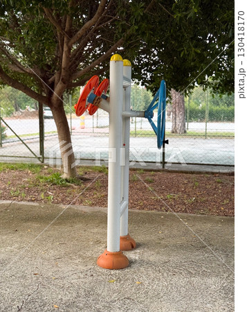 Outdoor training machine located near tennis court in park. Fitness, movement, and wellness showing community activity, strength, and health in daily lifestyle. Outdoor training machine located near tennis court in park. Fitness, movement, and wellness showing community activity, strength, and health in daily lifestyle. 130418170