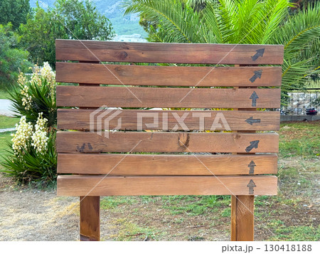 Closeup of wooden sign with multiple arrows set against palm background. Guidance, travel and orientation emphasizing navigation, tourism, and outdoor presence in natural landscape. Closeup of wooden sign with multiple arrows set against palm background. Guidance, travel and orientation emphasizing navigation, tourism, and outdoor presence in natural landscape. 130418188