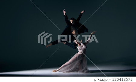 Male dancer soaring midair while female partner kneels in expressive pose 130418573