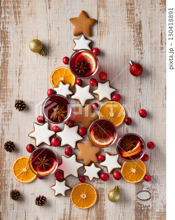 Christmas tree made of gingerbread cookies, mulled wine, cranberries, and dried oranges on wooden background. Creative festive flat lay.tree composition with mulled wine, cookies, oranges and 130418891