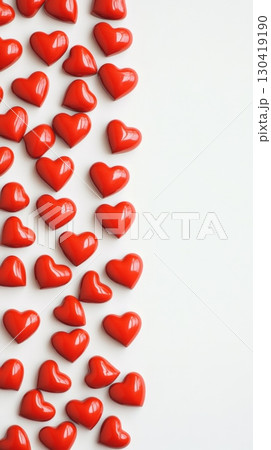 Small red heart shaped chocolates arranged in a vertical line on a white background creating a romantic atmosphere perfect for valentine's day, women's day, mother's day or anniversaries 130419190