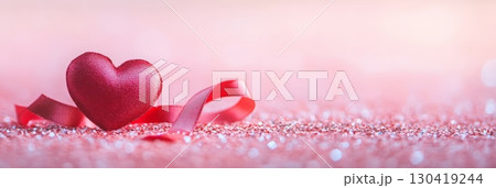 Red heart and ribbon are laying on a sparkling pink glitter background, creating a romantic atmosphere perfect for valentine's day, mother's day or spring celebrations 130419244