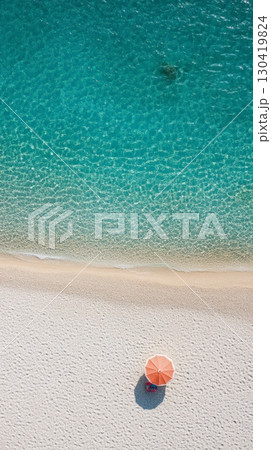 Aerial view of a single beach umbrella casting a shadow on a pristine white sand beach, gently kissed by crystal clear turquoise waters, creating a serene and idyllic vacation scene 130419824