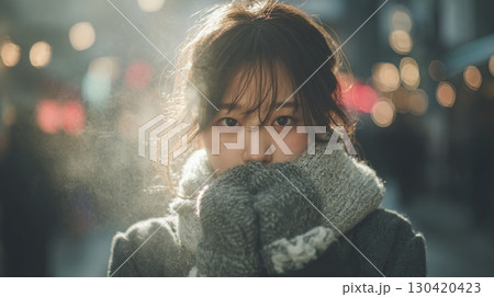 冷たい空気の中でマフラーに顔をうずめる女性｜冬,ポートレート,逆光,寒さ,温もり,街角 130420423