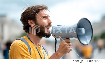 Young man with megaphone participating in a protest against immigration raids and ice policies, raising his voice for human rights and social justice in the united states 130420539
