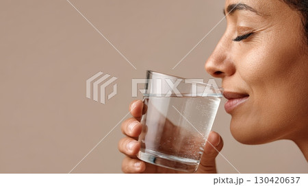 Close up profile of a woman enjoying a refreshing glass of detox water, promoting hydration and well being during the summer season with a focus on healthy lifestyle choices 130420637