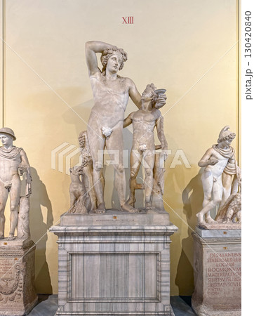 VATICAN CITY, ROME, ITALY - AUGUST 02, 2025 Statue of drunk Dionysus leaning on Satyr as holds a cup of wine in his hand. Ancient god of fertility hangs out with his woodland companion 130420840