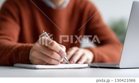 Close up of hands writing notes in notepad, working on laptop from home office, enjoying work and travel lifestyle as digital nomad, remote work and online education concept Close up of hands writing notes in notepad, working on laptop from home office, enjoying work and travel lifestyle as digital nomad, remote work and online education concept 130421066