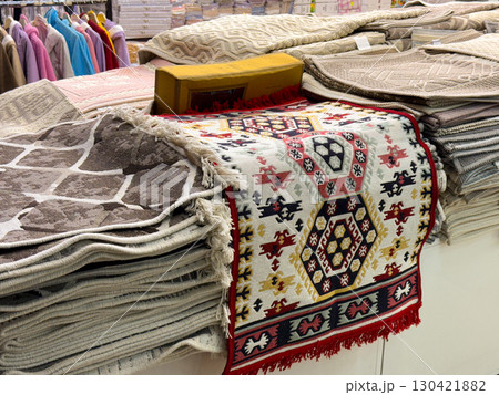 Stack of rugs with traditional patterns and colors folded in a market stall. Craftsmanship, culture and heritage represented through fabric design, artisan work and cultural identity 130421882