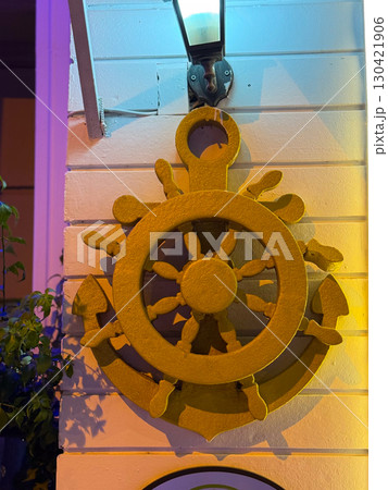 Anchor and helm symbol on a wall in warm evening light. Navigation, leadership and maritime heritage as a concept of direction, control and cultural identity. Anchor and helm symbol on a wall in warm evening light. Navigation, leadership and maritime heritage as a concept of direction, control and cultural identity. 130421906