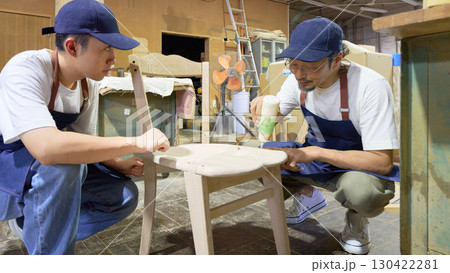 木工所で椅子を仕上げる職人と見習いのチームワーク 木工所で椅子を仕上げる職人と見習いのチームワーク 130422281