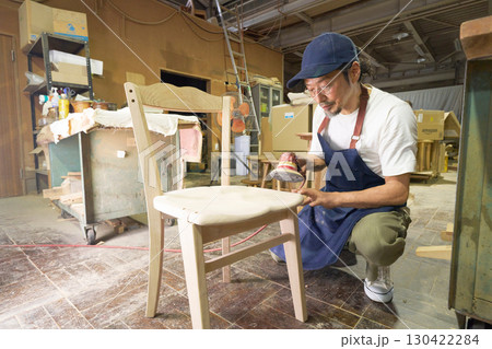 椅子を電動サンダーで仕上げる木工職人 130422284