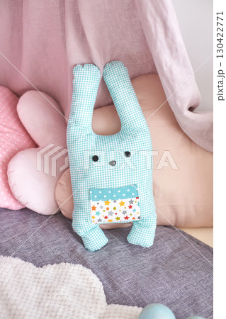 Soft blue checkered bunny toy in cozy pastel nursery setting with pillows Soft blue checkered bunny toy in cozy pastel nursery setting with pillows 130422771