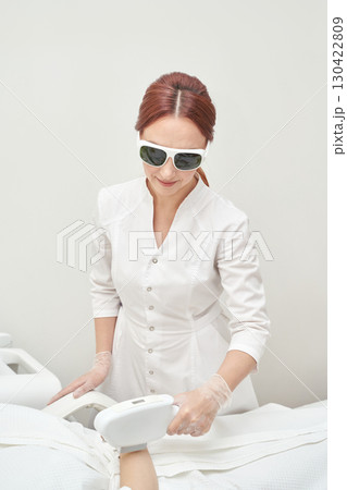 Female caucasian adult performing laser hair removal in clinical setting 130422809