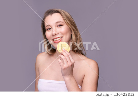 Young caucasian female smiling with cosmetic sponge in hand on purple background 130422812