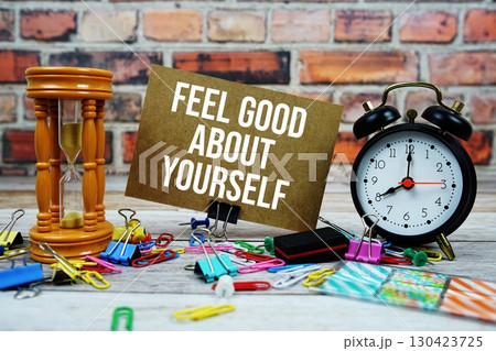 Feel Good About Yourself text on paper card with alarm clock and stationary on wooden background Feel Good About Yourself text on paper card with alarm clock and stationary on wooden background 130423725