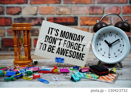 It's Monday Don't Forget To Be Awesome text on paper card with alarm clock and stationary on wooden background 130423732