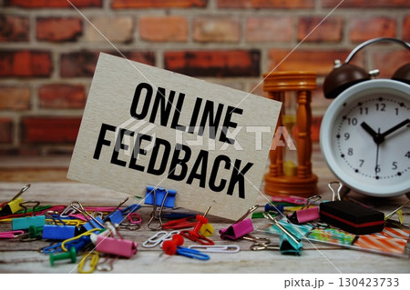Online Feedback text on paper card with alarm clock and stationary on wooden background Online Feedback text on paper card with alarm clock and stationary on wooden background 130423733