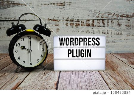 Wordpress Plugin text on light box with alarm clock on wooden background Wordpress Plugin text on light box with alarm clock on wooden background 130423884