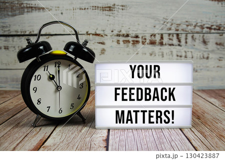 Your Feedback Matters! text on light box with alarm clock on wooden background 130423887