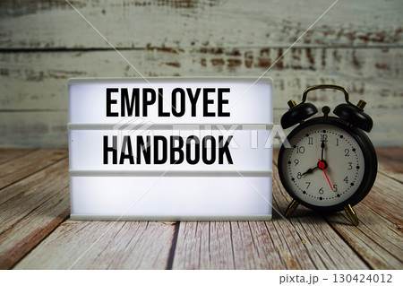 Employee Handbook text on light box with alarm clock on wooden background 130424012
