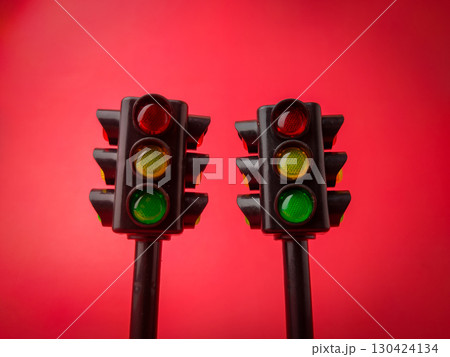 The image displays a two miniature traffic light on a red background. The image displays a two miniature traffic light on a red background. 130424134