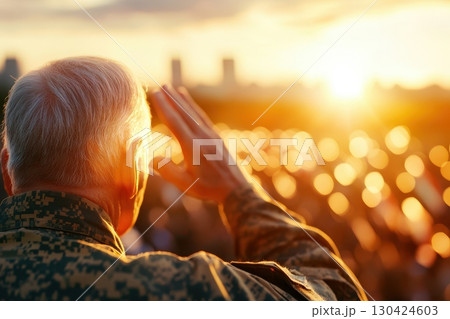 A senior military veteran salutes at sunset, bathed in golden light, reflecting on service and remembrance 130424603