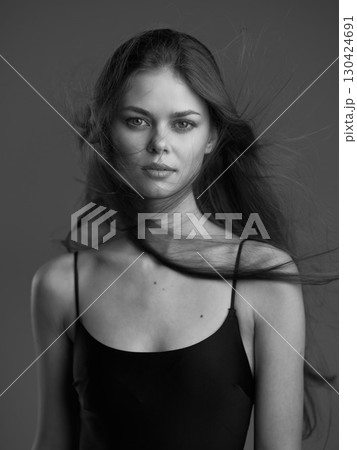 Black and white portrait of a young woman with long hair and serious expression wearing a black top. 130424691