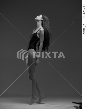 Black and white elegant woman in bodysuit posing with upward gaze in studio setting with minimalistic background. Black and white elegant woman in bodysuit posing with upward gaze in studio setting with minimalistic background. 130424716