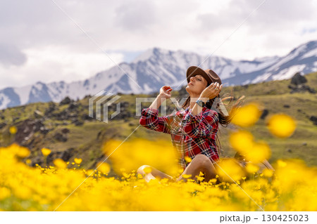Flowers field woman mountain: Girl in flower meadow, with mountains, relaxes in nature. 130425023