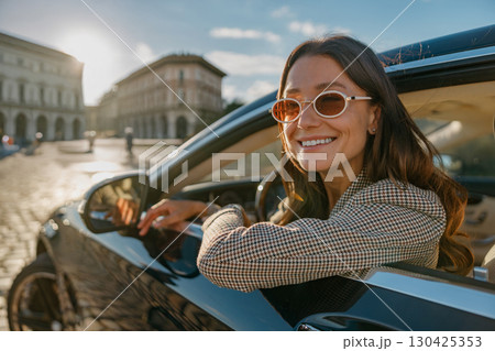 Joyful Young Woman Delightedly Enjoying a Scenic Drive Through the Beautiful City Streets 130425353