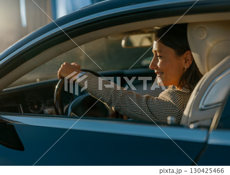 A woman is joyfully driving her car during a beautiful sunset, experiencing pure bliss A woman is joyfully driving her car during a beautiful sunset, experiencing pure bliss 130425466