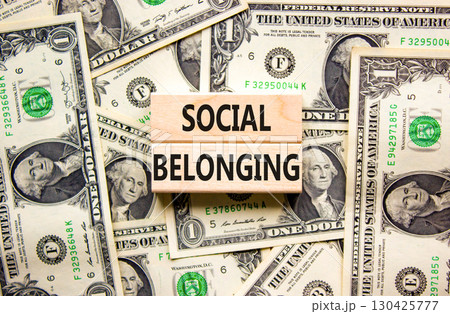 Social belonging symbol. Wooden blocks with concept words Social belonging on beautiful background from dollar bills. Business political social belonging concept. Copy space. 130425777